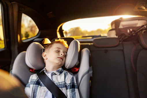 A child is sleeping in his car seat in vehicle.