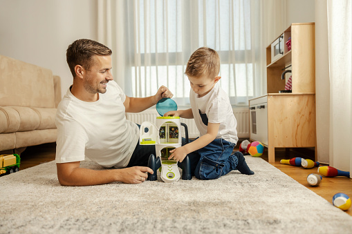 A child and his father are playing with space ship toy at home and having fun.