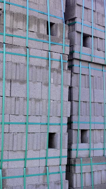 Block stacks as building material at site. Building material in block form, palletized. Construction site with block building material, unfinished structure background