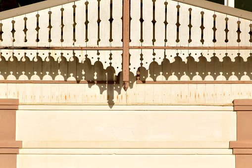 Noumea, South Province, Grande Terre island, New Caledonia: gable with ornate wooden fretwork (lambrequins), traditional of the local vernacular architecture. The late afternoon sun casts detailed shadows of fretwork onto the warm-toned wall of a building.