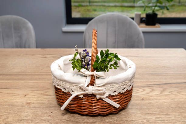 an empty wicker easter basket, decorated with boxwood and catkins, standing on a table. - picnic basket christianity holiday easter - fotografias e filmes do acervo
