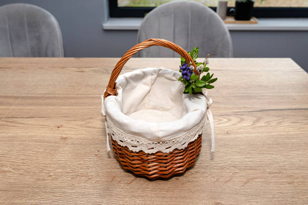 an empty wicker easter basket, decorated with boxwood and catkins, standing on a table. - picnic basket christianity holiday easter fotografías e imágenes de stock