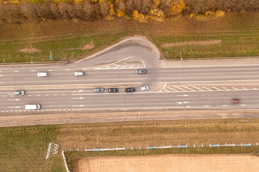 Drone photography of an U turn in a highway and cars turning during autumn sunny day