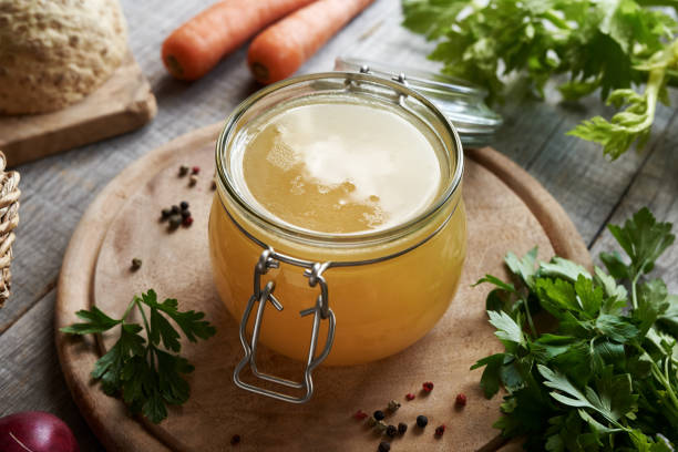 istock Bone broth in a glass jar on a table, with vegetables in the background 1965634687