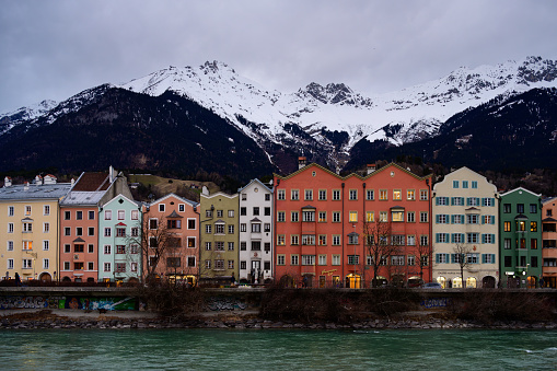 Innsbruck, Austria - January 24 2024: Medievial Colorful Houses in Mariahilf with Inn River and Nordkette Mountains on a Winter Evening.