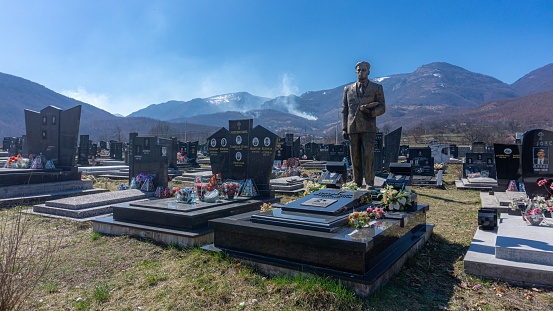Berane, Montenegro-22 March, 2019: A cemetery, burial ground, graveside, graveyard, a place where the remains of dead people are buried,  cultural practices and religious beliefs. Small local graveyard on a countryside during sunny day with stone and marble slab for remembering the deads.