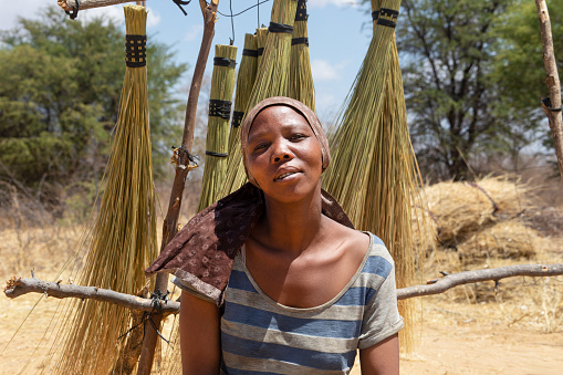 entrepreneur african woman in the village , selling brooms on the side of the highway to the cars passing by
