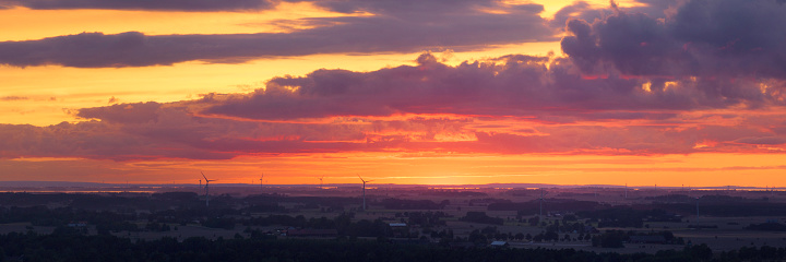 Wind turbines in a landscape on an evening with a colorful sunset in the Östergötland region of Sweden.