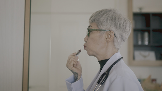 doctor puts lipstick on her mouth during his lunch break.