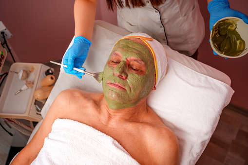 clay mask applied to a Senior man at a wellness spa using a special brush