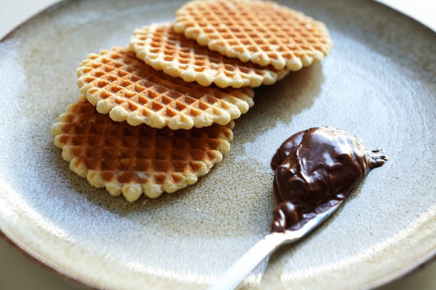 Round waffle cookies and chocolate cream on a plate with a white background