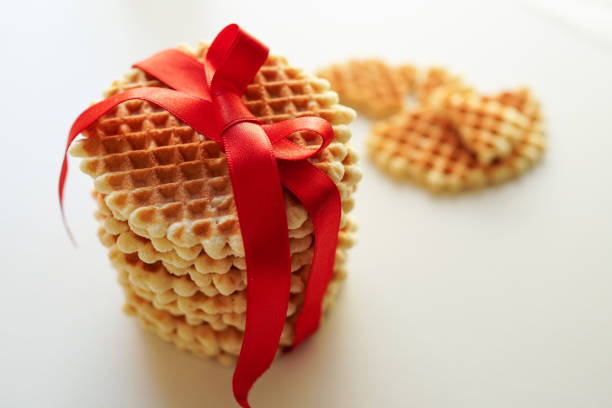 Round waffle cookies wrapped with red ribbon on a white background