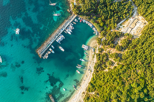 Port, pier, dock with boats, cruise ship in blue, turquoise sea water. Summer vacations and travel concept. Marina. Aerial, drone view