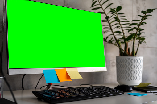 Green screen office monitor, with sticky note on it