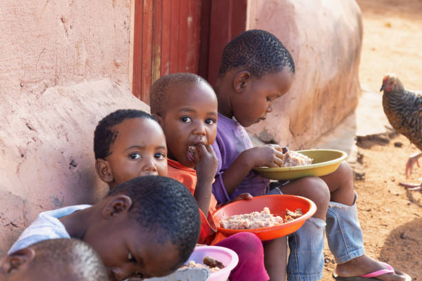 group of village african children eating in the yard, famine and malnutrition NGO solving world problems