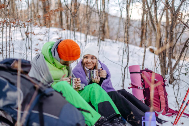 istock Couple taking a break from hiking on snow during winter days having refreshment drink 1965826424