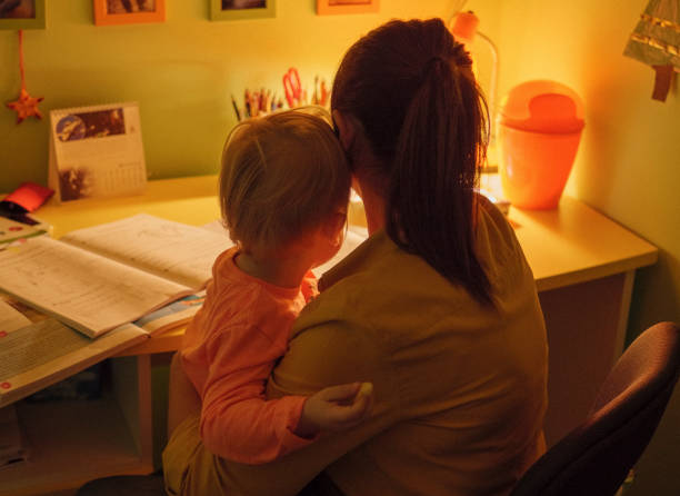 mother holds her baby while working at the desk