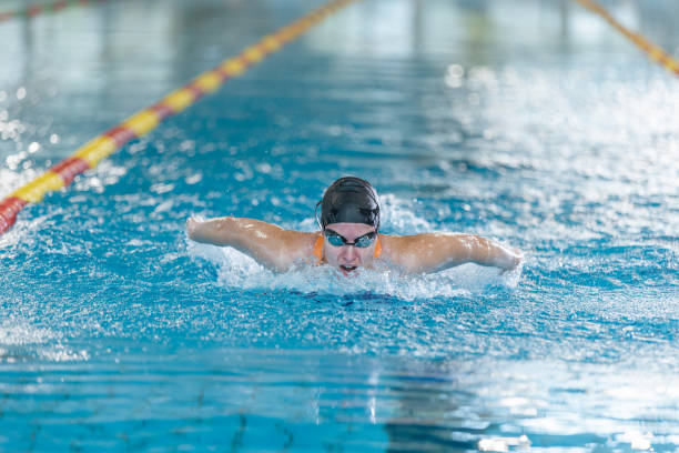 Asian chinese female Swimmer practicing butterfly stroke, Swimming in lap Pool. Professional Athlete Determined to Win Championship