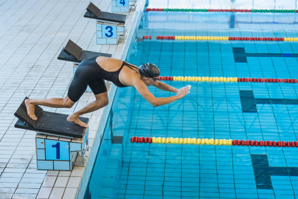 istock Female swimmer jumping into a pool from the starting block 1965866744