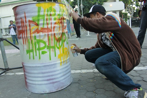 Yogyakarta, Indonesia, June 24, 2012. Young man express themselves by drawing using spray paint on used oil barrels.
