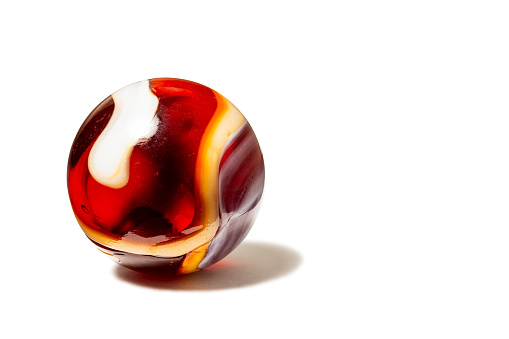 A red, white, and orange swirl glass marble with shadow on white.