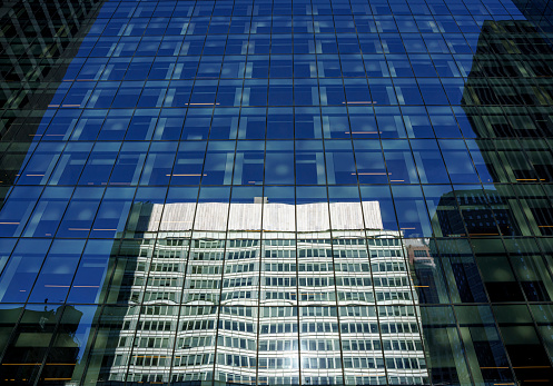 Low angle view of modern office buildings reflected in glass windows in New York City