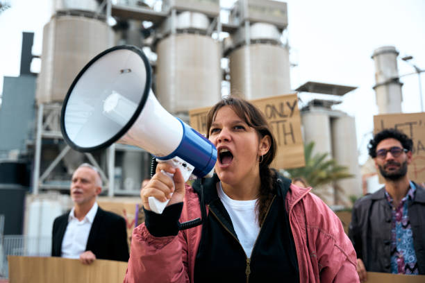 Angry and rebellious woman speaking and protesting with megaphone at demonstration at climate change