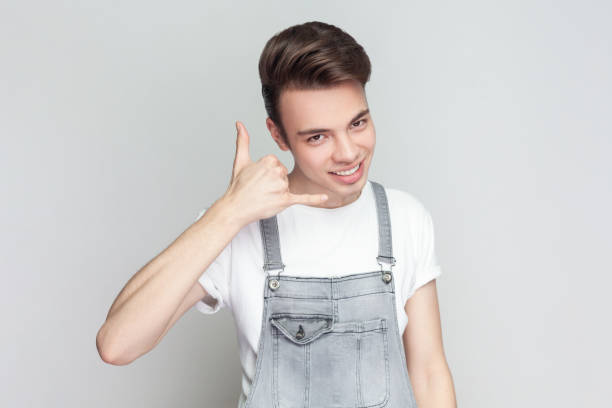 istock Cheerful joyful brunette man standing makes call me back gesture has optimistic face expression. 1966120901