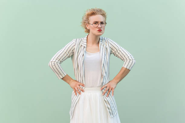 istock Strict bossy blonde woman looking at camera with serious expression, keeps hands on hips. 1966123568
