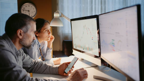 Stock trading. Couple on TradingView app at home office.