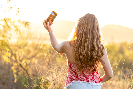 Teen taking selfie in a sunny field