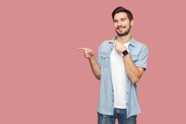 istock Man points away on copy space, discusses amazing promo, give way or direction, has pleasant smile. 1966126203