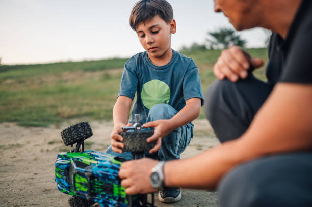 istock Son and father using tool to fix toy car outdoors. 1966145140