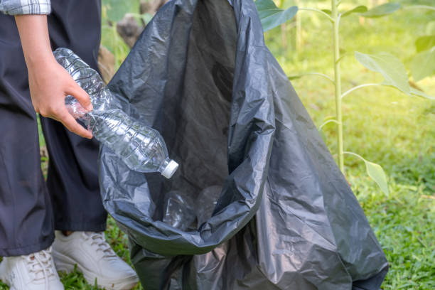 istock Hand holding plastic bottle waste, picking up trash putting to the black garbage bag at Sunflower Park on Environmental Earth day 1966145685