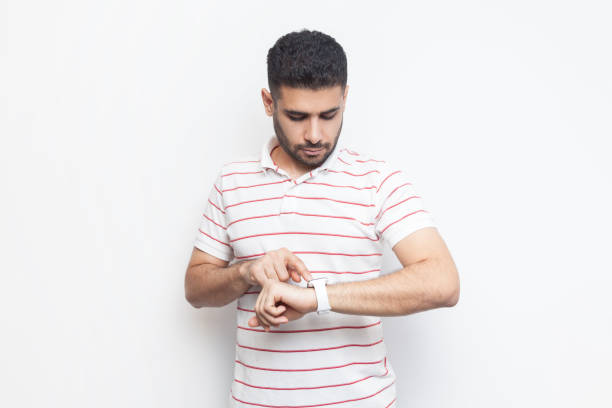 istock Concentrated bearded man wearing striped t-shirt standing using his smart watch, uses application. 1966167453