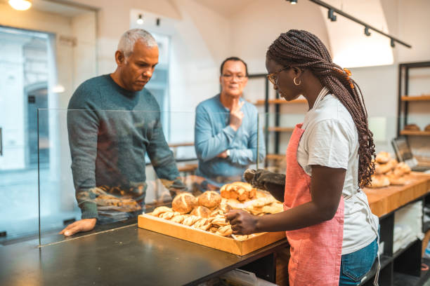 istock Cheerful Black Female Serving Customers In An Artisan Bakery 1966175766