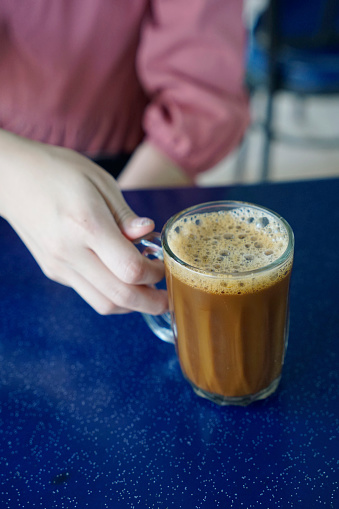 Cropped woman's hand holding a mug of Malaysian coffee