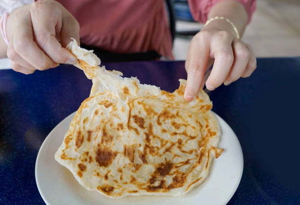 istock Womans hands tearing a Roti Canai flatbread for breakfast 1966247430