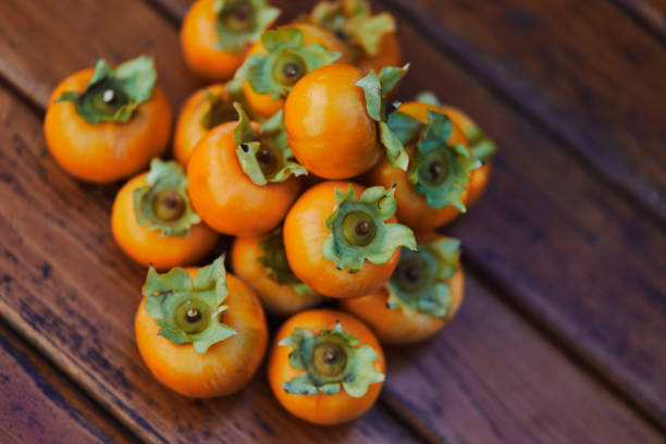 istock Stack of orange persimmon lies on an old wooden table. Top view 1966338314