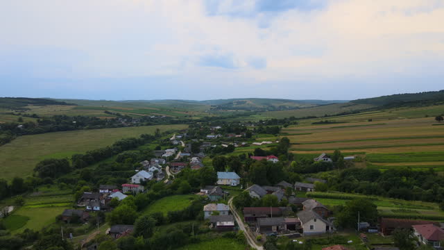 Ukrainian village houses between green cultivated agricultural fields in rural area