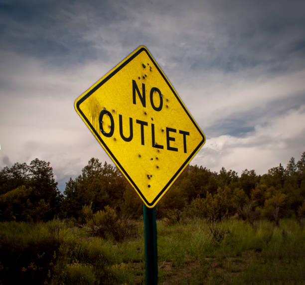 A road sign stating No Outlet riddled with bullet holes A road sign stating No Outlet riddled with bullet holes end gun violence stock pictures, royalty-free photos & images