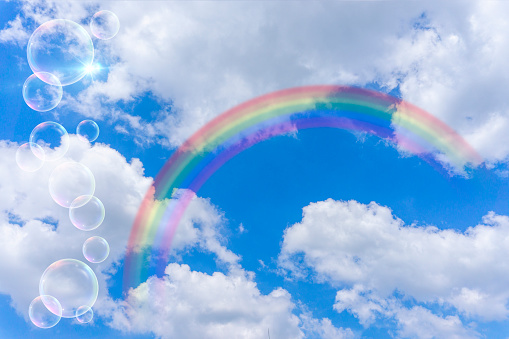 Background material of blue sky with rainbow, clouds and soap bubbles