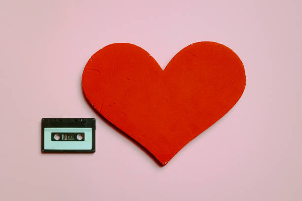 Heart Next to an Audio Cassette on a Colorful Pink Background Beautiful design of romantic music old school mixtape concept mix tape heart stock pictures, royalty-free photos & images