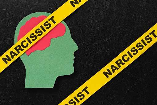 Human head profile with word narcissist in dark black background. Narcissistic behavior concept.