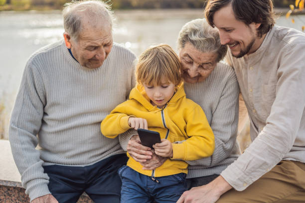 the boy shows the photo on the phone to his grandparents - 11902 stock-fotos und bilder