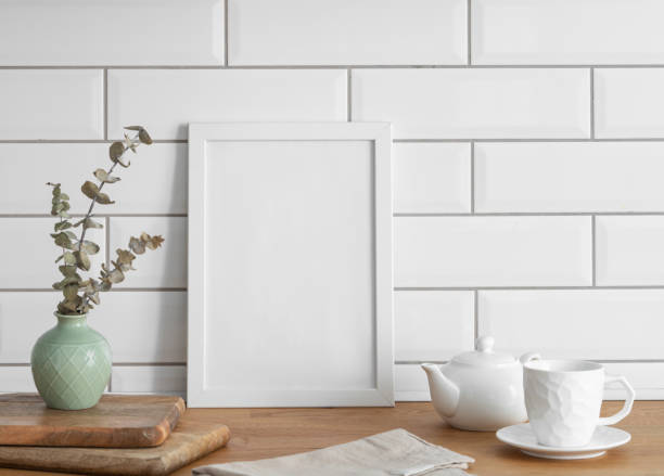 A  frame with a blank canvas against a white tile wall and on a wooden tabletop