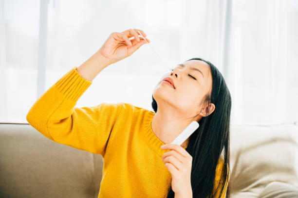 istock Woman at home uses a rapid antigen test kit inserting a swab into her nose 1966775434