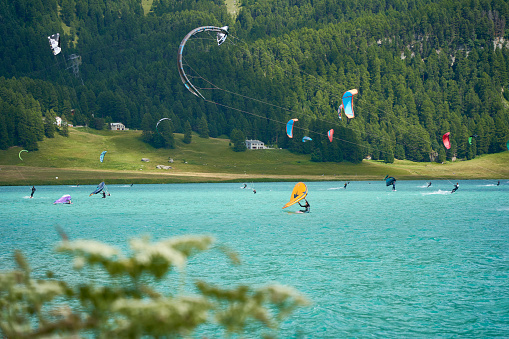 Engadin, Switzerland - July 16, 2023: Wind also wing surfing and kite boarding on lake silvaplana. Lots of water sports and athletes on the Water. Summer day in the Mountains. Swiss, Sankt Moritz.