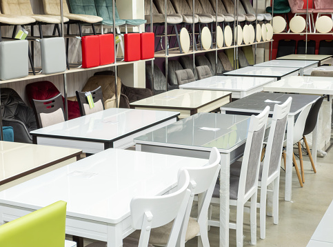 A large warehouse of chairs and tables in a shopping center. Furniture store. Sale of tables and chairs. Different types of chairs in the interiors store.