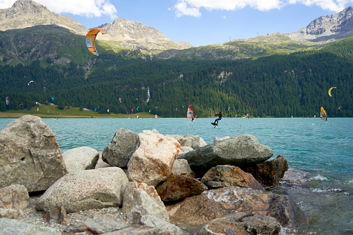 Engadin, Switzerland - July 16, 2023: Wind also wing surfing and kite boarding on lake silvaplana. Lots of water sports and athletes on the Water. Summer day in the Mountains. Swiss, Sankt Moritz.